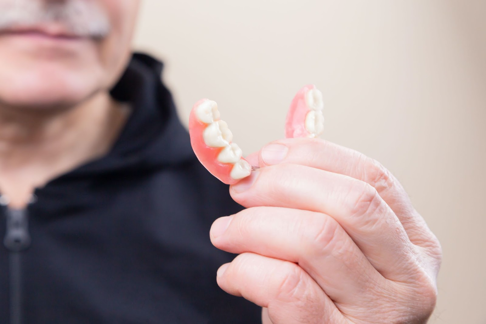 Man holding a denture for tooth loss
